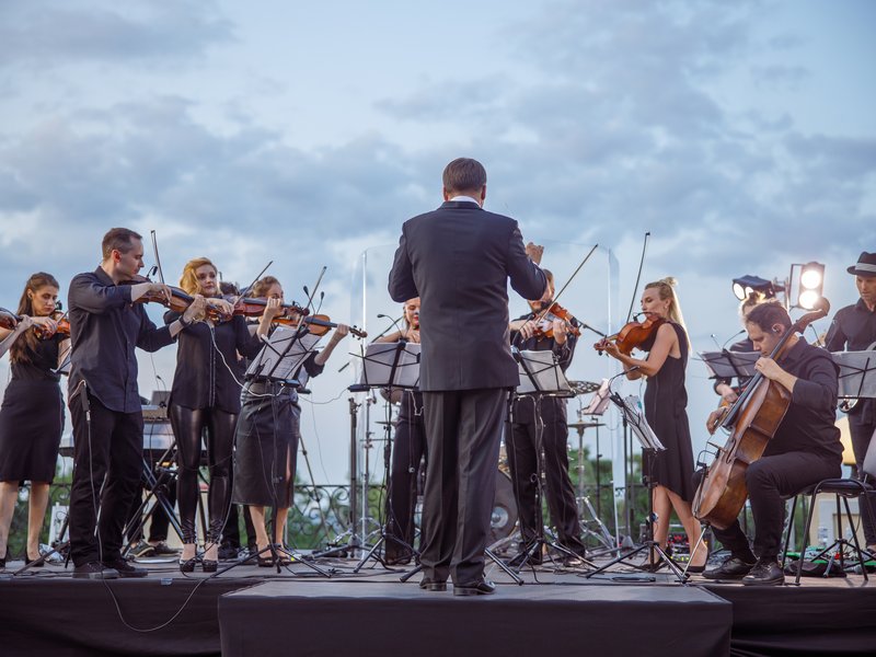 Conductor leading a full orchestra on an outdoor stage